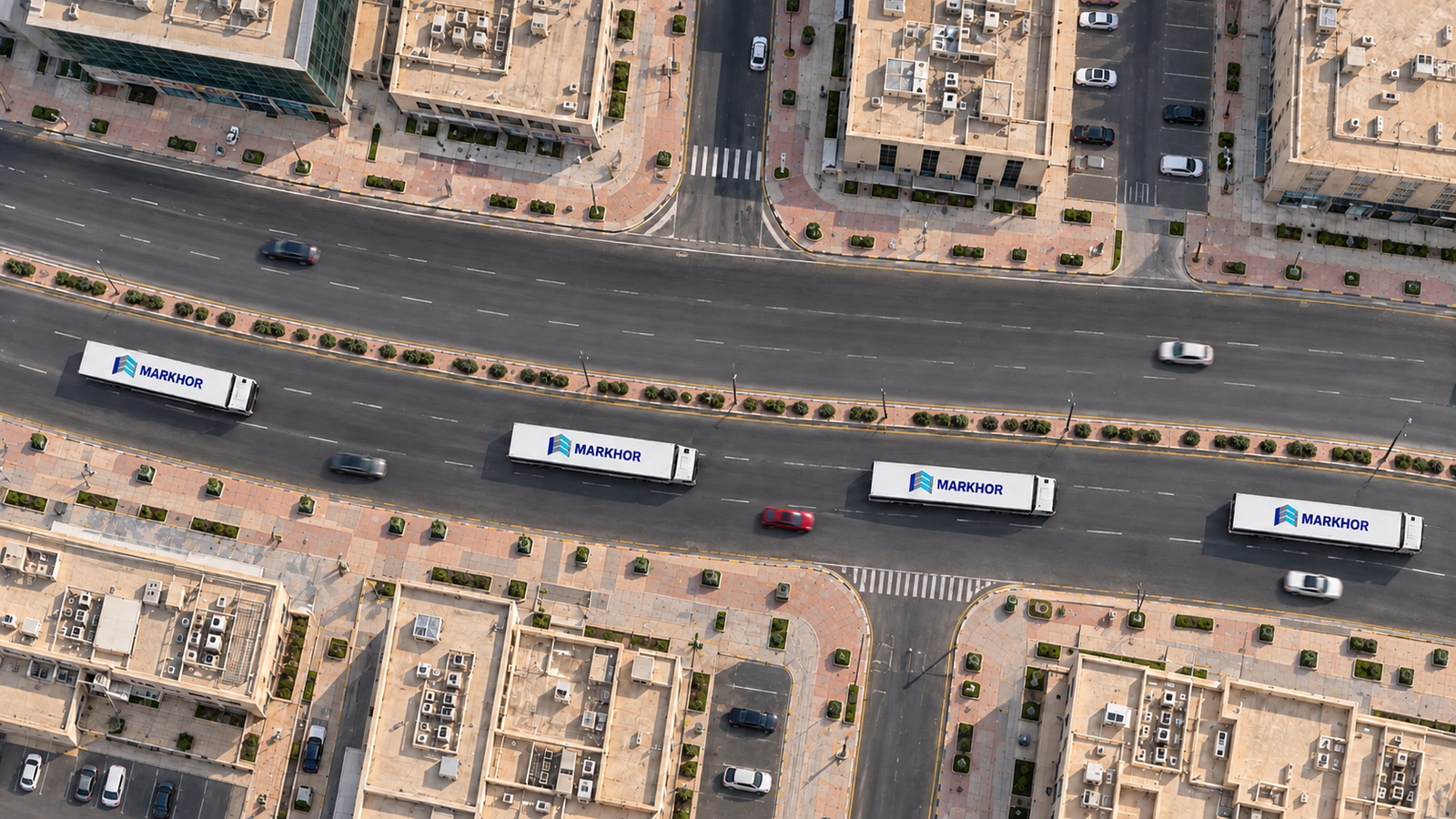 Top-down drone view of Markhor trucks on a city road with light traffic and surrounding buildings